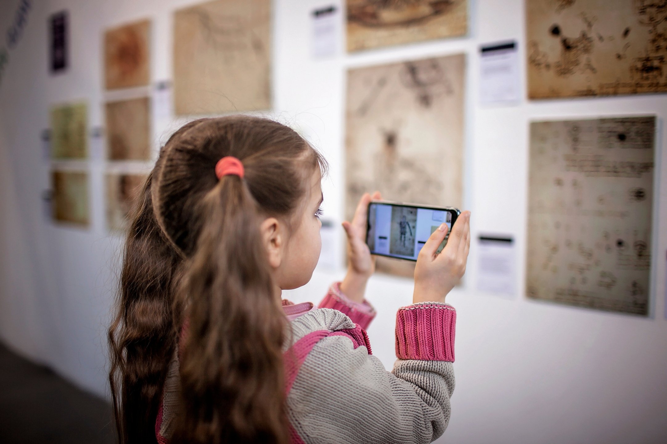 Curious Girl Exploring a Contemporary Art Exhibition with Augmented Reality Mobile Application